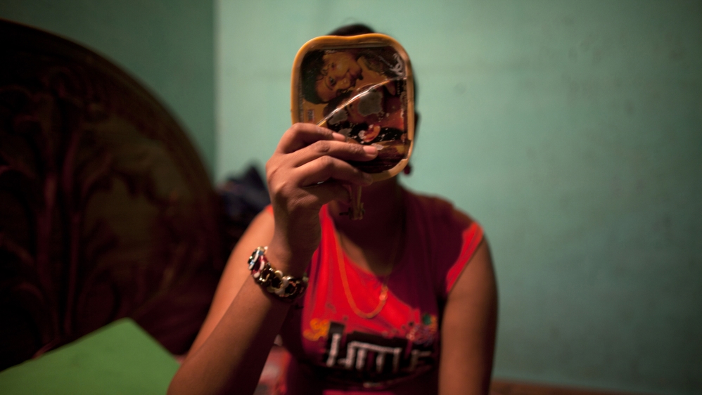 Twelve-year-old prostitute Mukti applies makeup before serving a customer inside her small room at a brothel in Faridpur, located in central Bangladesh