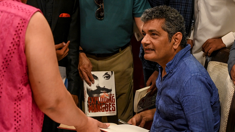 In this picture taken on September 28, 2019 Mohammed Hanif (C), the former fighter pilot turned journalist, gives autographs to his fans during a literature festival in Islamabad. - Featuring bumbling