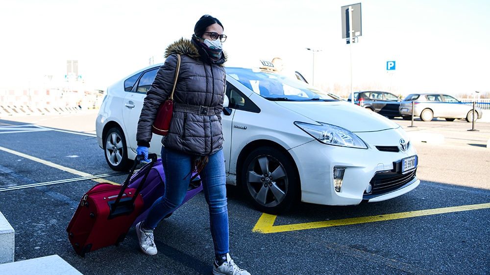 A passenger wearing a protective face mask, amid concerns about the COVID-19 outbreak, walks in Linate Airport in Milan on March 8, 2020, after millions of people were placed under forced quarantine i
