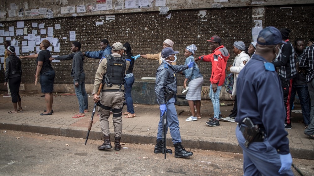 A police officer enforces social distancing as he makes shoppers stretch their arms in front of them to ensure that they are at least one metre apart from one anot
