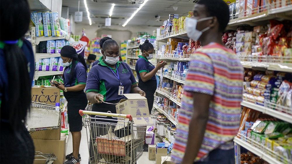 Shop assistants wearing face masks to prevent against the spread of the new coronavirus take stock in a supermarket in Lagos, Nigeria Friday, March 27, 2020. The new coronavirus causes mild or moderat