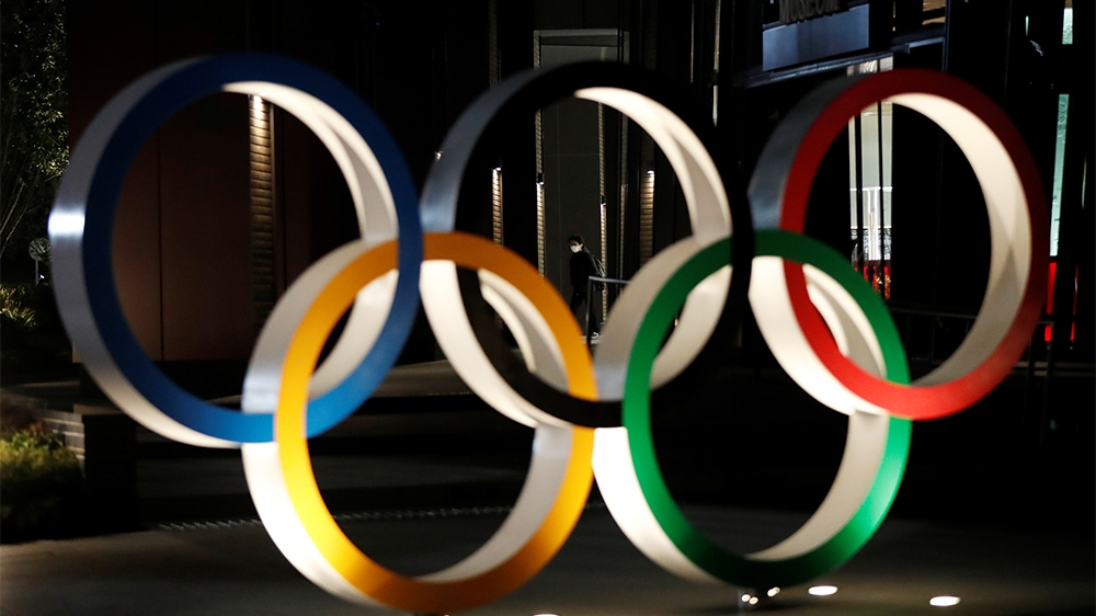 A passerby wearing a protective face mask, following an outbreak of the coronavirus disease (COVID-19), walks past the Olympic rings in front of the Japan Olympics Museum in Tokyo, Japan March 24, 202