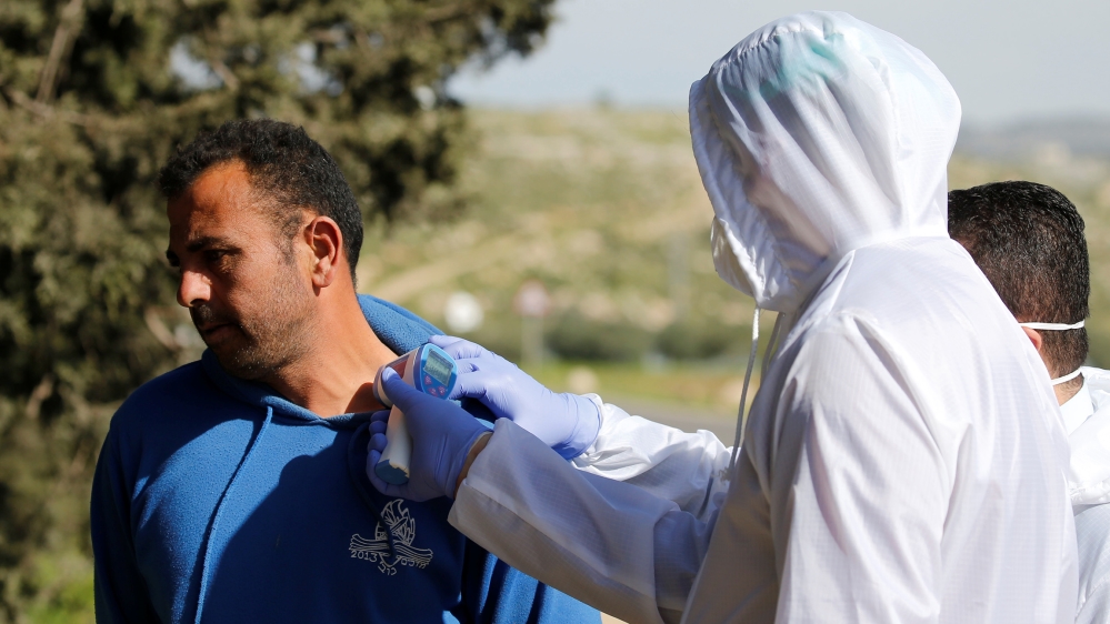 A member of medical staff checks the body temperature of a Palestinian worker returning from Israel, amid concerns over the spread of the coronavirus disease (COVID-19), outside the Israeli-controlled