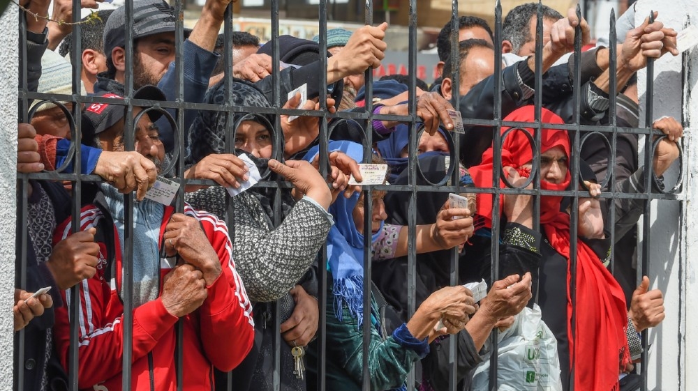 Impoverished Tunisian citizens gather with their identification cards in front of the headquarters of Mnihla delegation in Ariana Governorate outside Tunis on March 30, 2020,