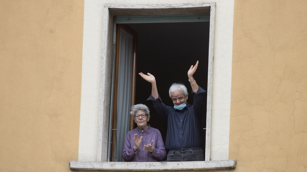 People clap their hands and wave, in Rome, Saturday, March 14, 2020. At noon in Italy, people came out on their balconies, terraces, gardens or simply leaned out from open windows to clap for several
