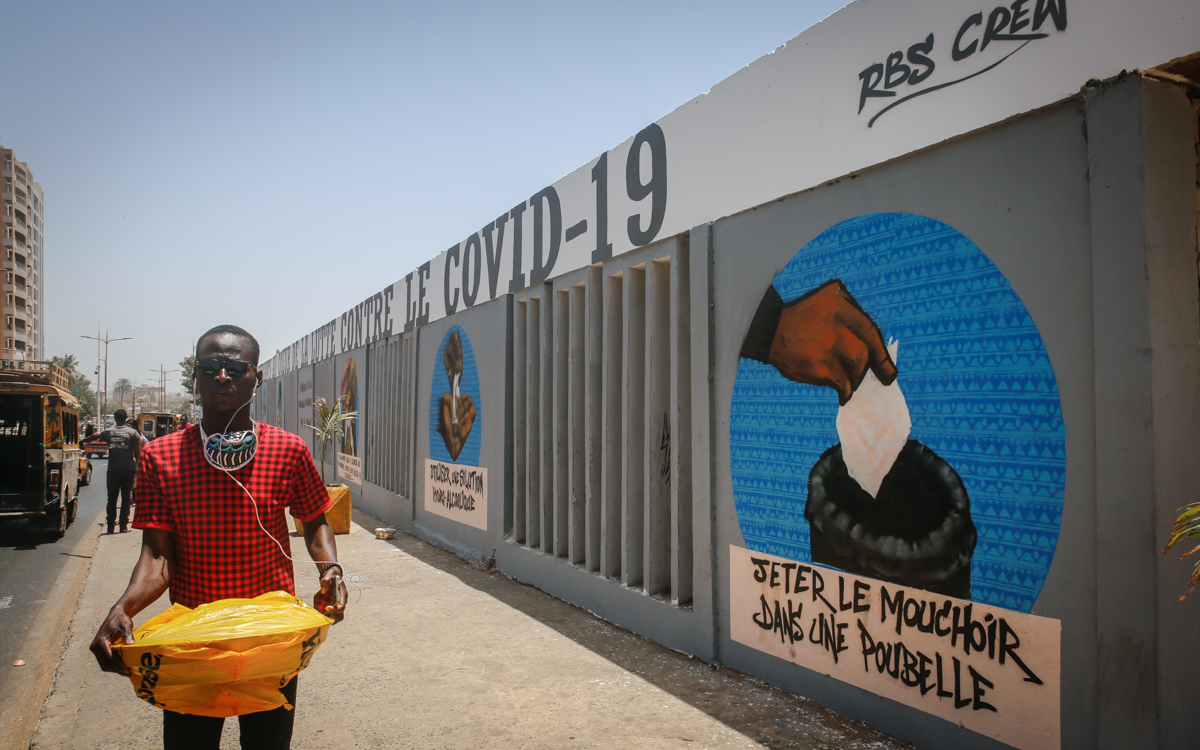 A man walks past a mural depicting a set of good hygiene practices for preventing Covid-19 that has been painted on the walls of Dakar’s main university campus by graffiti group RBS. The message visib