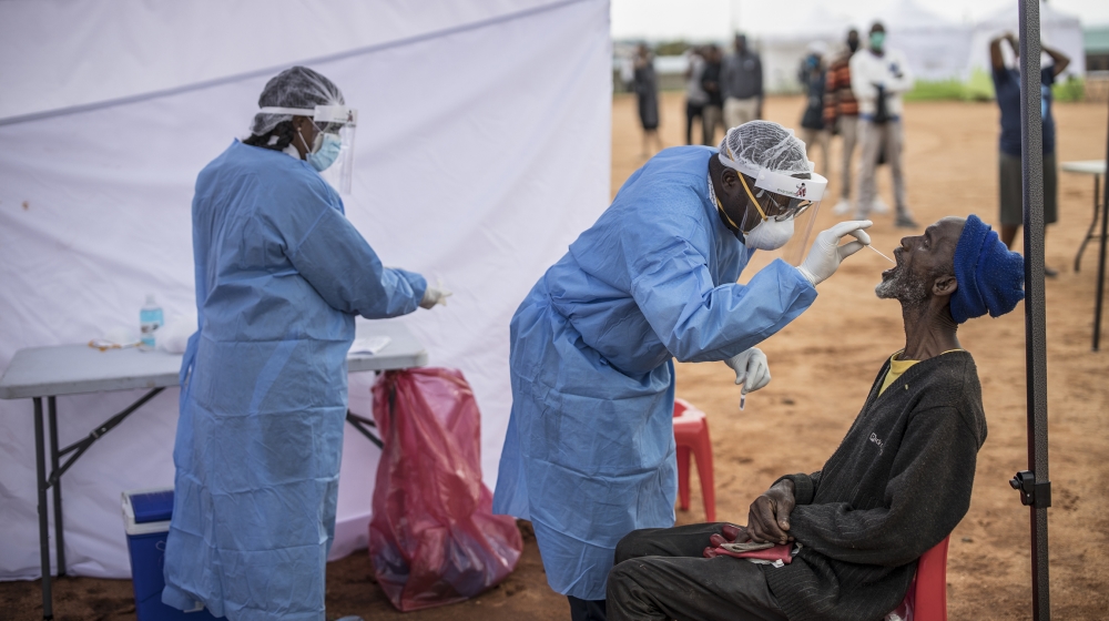 An elderly man, a resident of the sprawling township of Alexandra in Johannesburg, opens his mouth to receive a testing swab for COVID-19 coronavirus at a screening and testing drive in front of the M