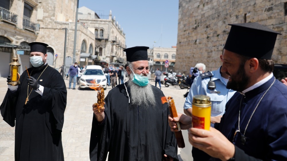 Greek Orthodox priests hold candles lit from the Holy Fire in the church of the Holy Sepulchre, as very few Orthodox Christians gather in Jerusalem''s Old City to celebrate Easter