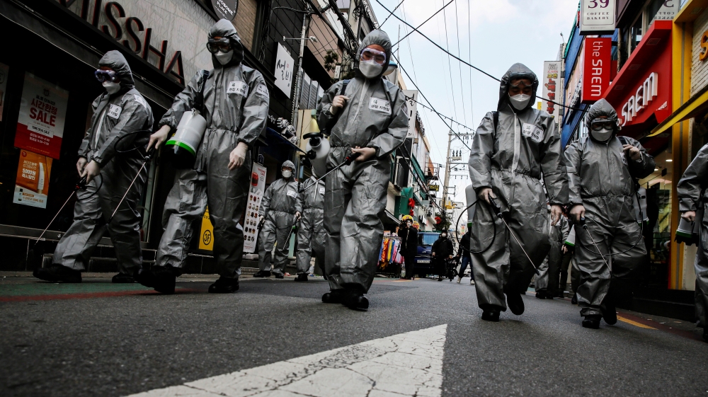 South Korean soldiers in protective gear sanitize a shopping street in Seoul