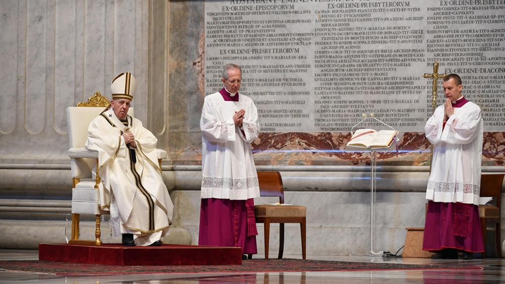 epa08358478 Pope Francis (L) looks on as he celebrates Easter Sunday Mass behind closed doors at St. Peter's Basilica in The Vatican, 12 April 2020. The mass is held behind closed doors during the loc