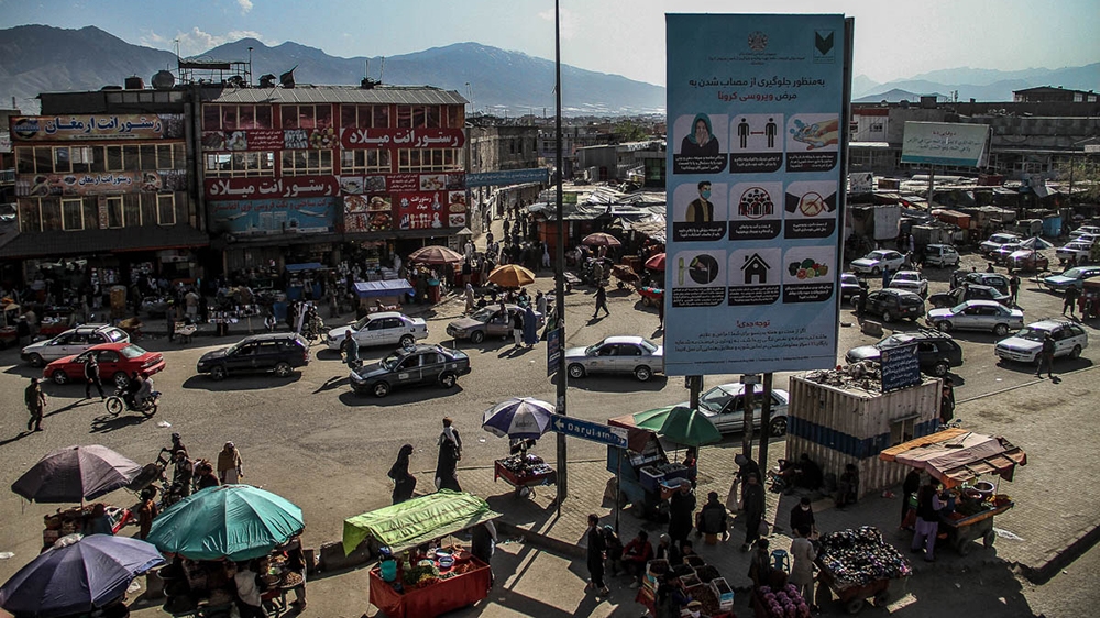 A sign with anti-coronavirus measures over a busy bazaar in Kabul [Agnieszka Pikulicka-Wilczewska/Al Jazeera]