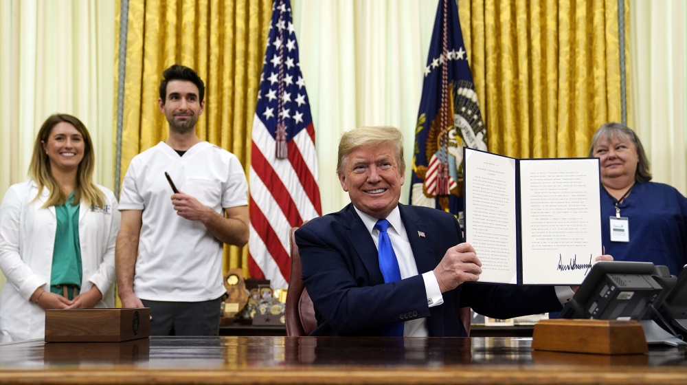 President Donald Trump holds a signed proclamation in honor of World Nurses Day during an event in the Oval Office of the White House, Wednesday, May 6, 2020, in Washington. (AP Photo/Evan Vucci)