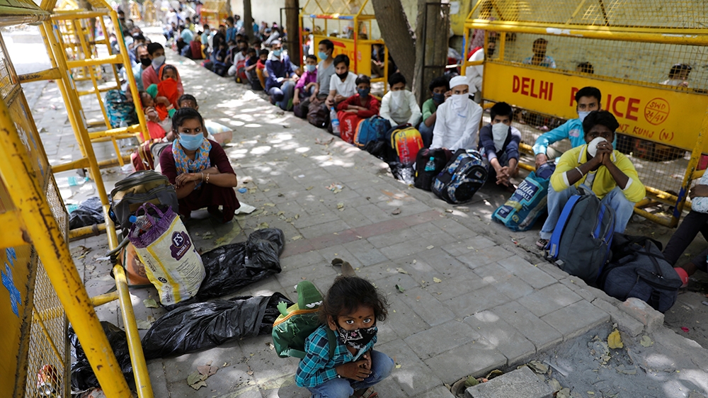 Migrant workers and their families wait to get on a bus to reach a railway station to board a train to their home state of Uttar Pradesh, during an extended lockdown to slow the spreading of the coron