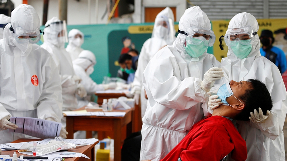Healthcare workers take a swab sample from a passenger amid the coronavirus disease (COVID-19) outbreak, at a commuter train station in Bogor near Jakarta, Indonesia, May 11, 2020. REUTERS/Ajeng Dinar