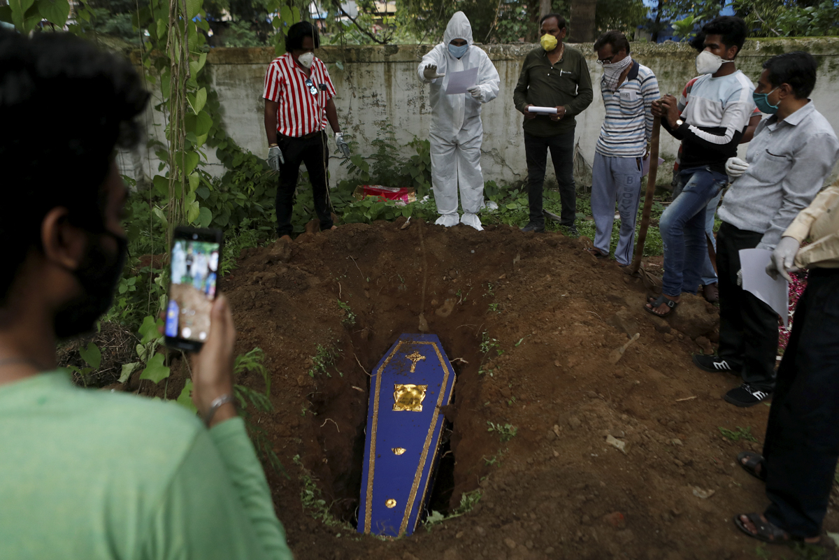 A priest wearing personal protective equipment (PPE) prays over the coffin of a person who died from the coronavirus disease (COVID-19) during a funeral at a cemetery in Mumbai, India June 27, 2020. R