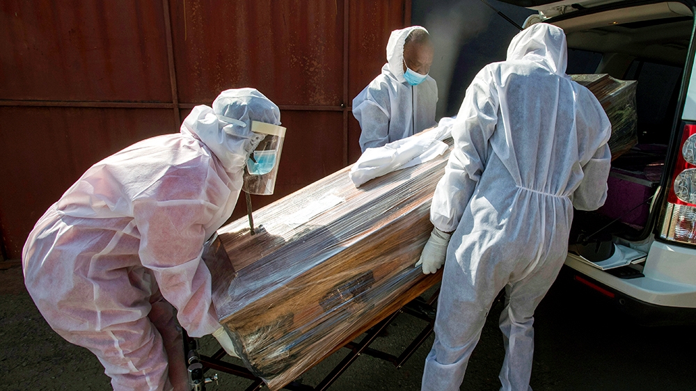 Maziya funeral home workers in protective suits carries a confine of a woman who died from COVID-19 unto a hearse in Katlehong, near Johannesburg, South Africa, Tuesday, July 21, 2020. South Africa,