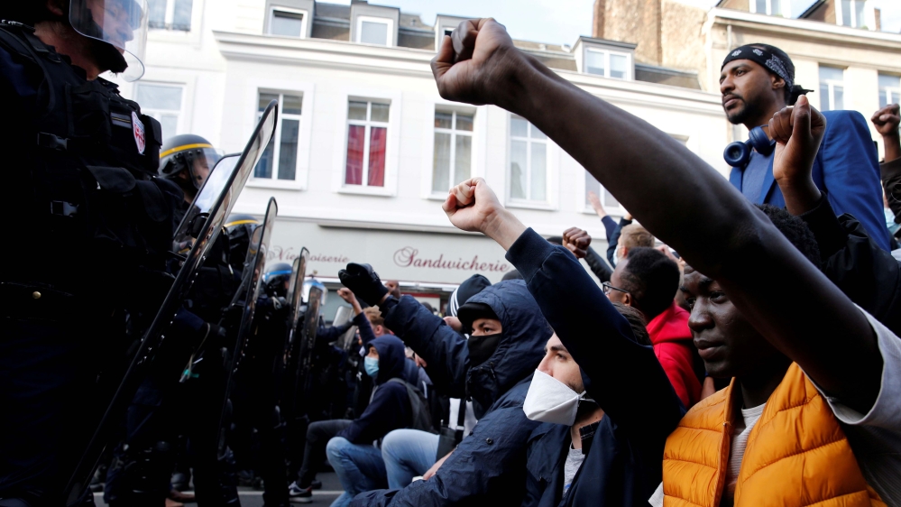 Protesters raise their fists during a banned demonstration in memory of Adama Traore,