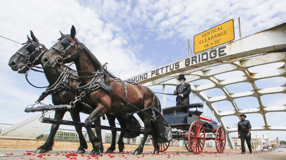 The casket of Rep. John Lewis moves over the Edmund Pettus Bridge by horse drawn carriage during a memorial service for Lewis, Sunday, July 26, 2020, in Selma, Ala. Lewis, who carried the struggle aga