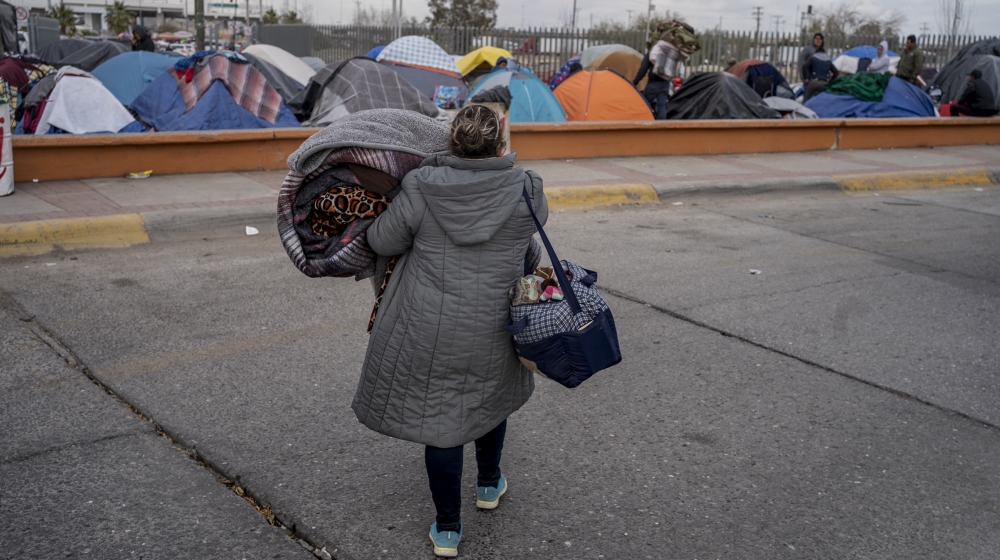 A woman carries belongings to a different part of the campsite near US ports of entry at Chamizal Park on December 19, 2019 in Ciudad Juarez, Mexico. In the mud and biting cold of a makeshift camp in