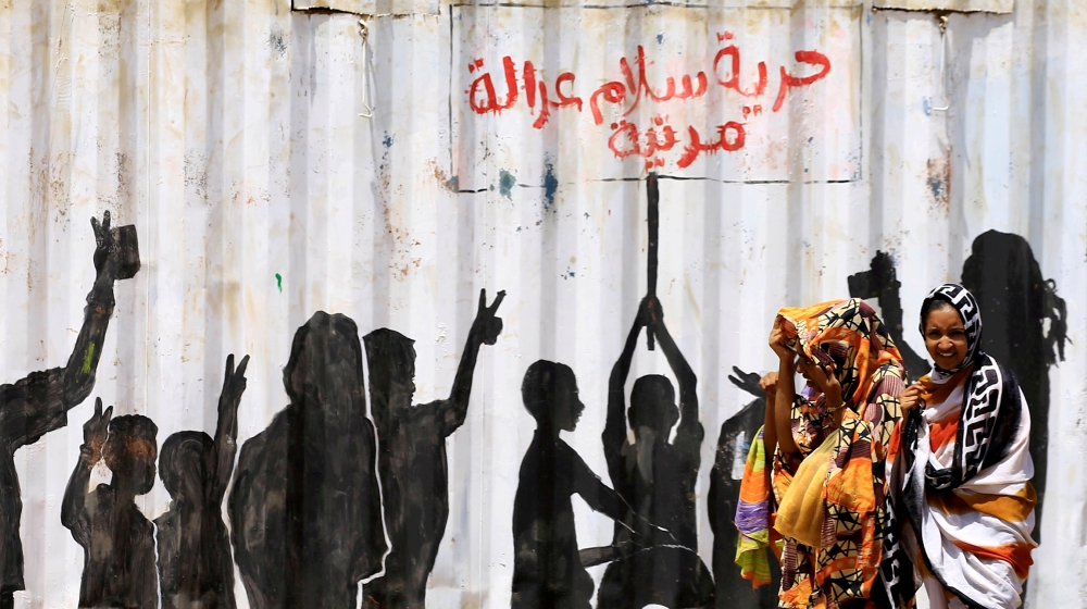 Civilians walk past graffiti reading in Arabic "Freedom, Peace, Justice and Civilian" in the Burri district of Khartoum, Khartoum, Sudan, July 10, 2019. REUTERS/Mohamed Nureldin Abdallah