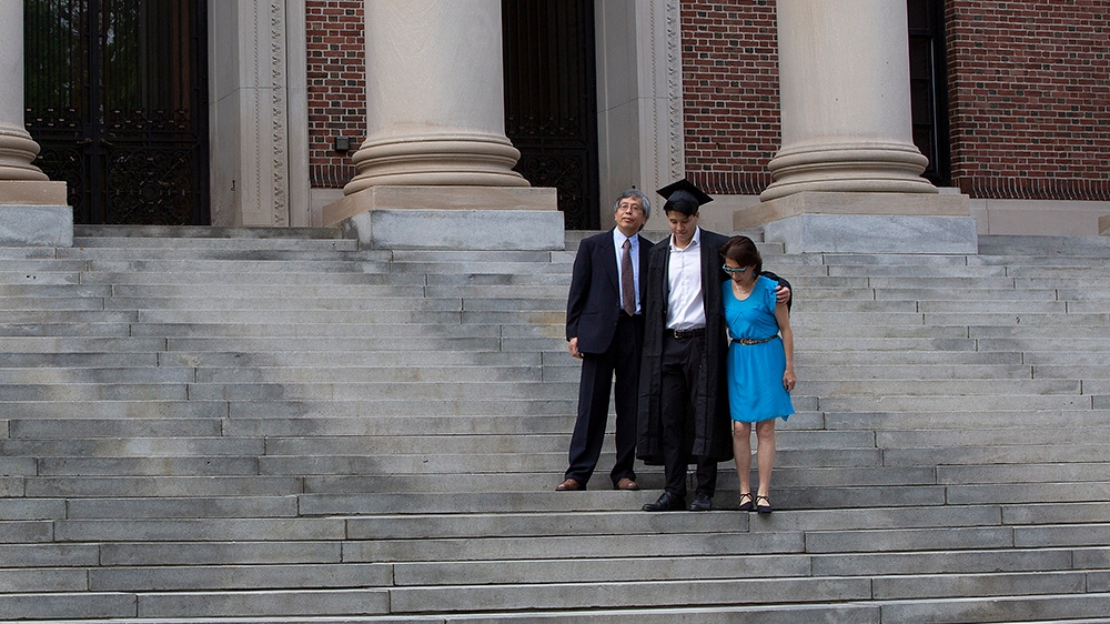 epa08450052 Harvard College Class of 2020 Graduate Tyler Yan (C) along with his parents James Yan (L) Min Chang (R) pose for photo on the stairs of the Widener Library on what would have been the 369t