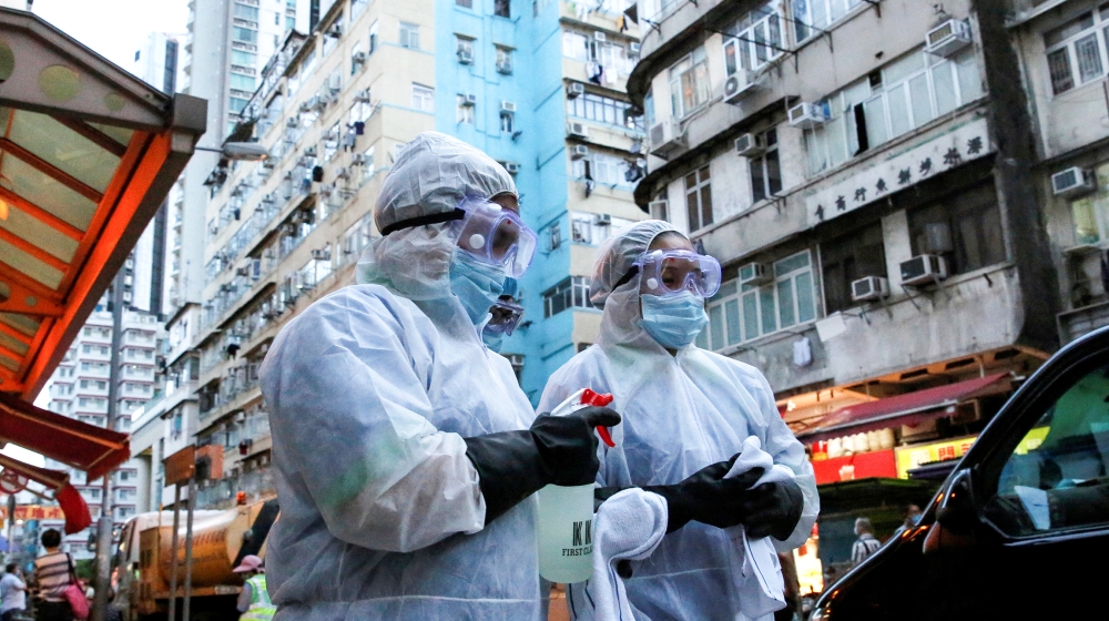 Cleaning workers wearing protective gear walk past a wet market following the coronavirus disease (COVID-19) outbreak at Sham Shui Po, one of the oldest districts in Hong Kong, China July 17, 2020. RE