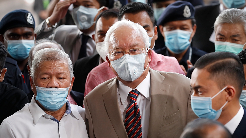 Former Malaysian Prime Minister Najib Razak, center, wearing a face mask prays with his supporters upon arrival at court house in Kuala Lumpur, Malaysia, Tuesday, July 28, 2020. Malaysian High Court t