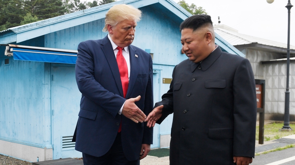 Donald Trump shakes hands with North Korean leader Kim Jong Un