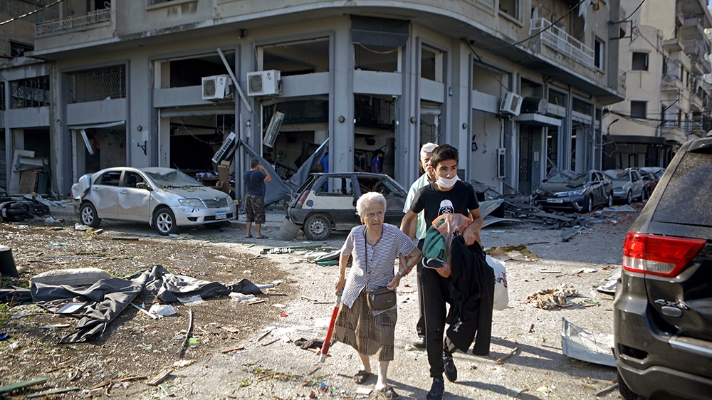 A woman is evacuated from the partially destroyed Beirut neighbourhood of Mar Mikhael on August 5, 2020 in the aftermath of a massive explosion in the Lebanese capital. - Rescuers searched for survivo