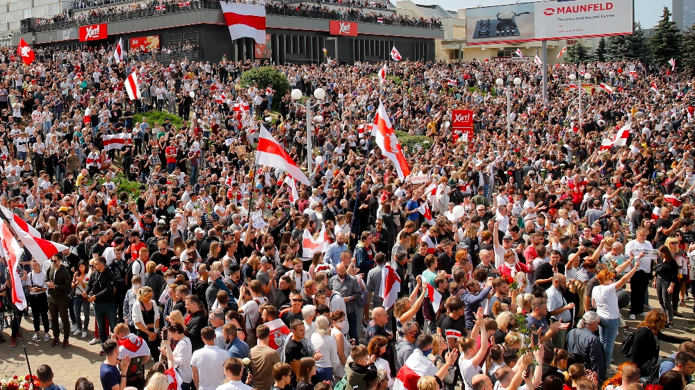 People hold old Belarusian National flags and gather at the place where Alexander Taraikovsky died amid the clashes protesting the election results, during his civil funeral in Minsk, Belarus