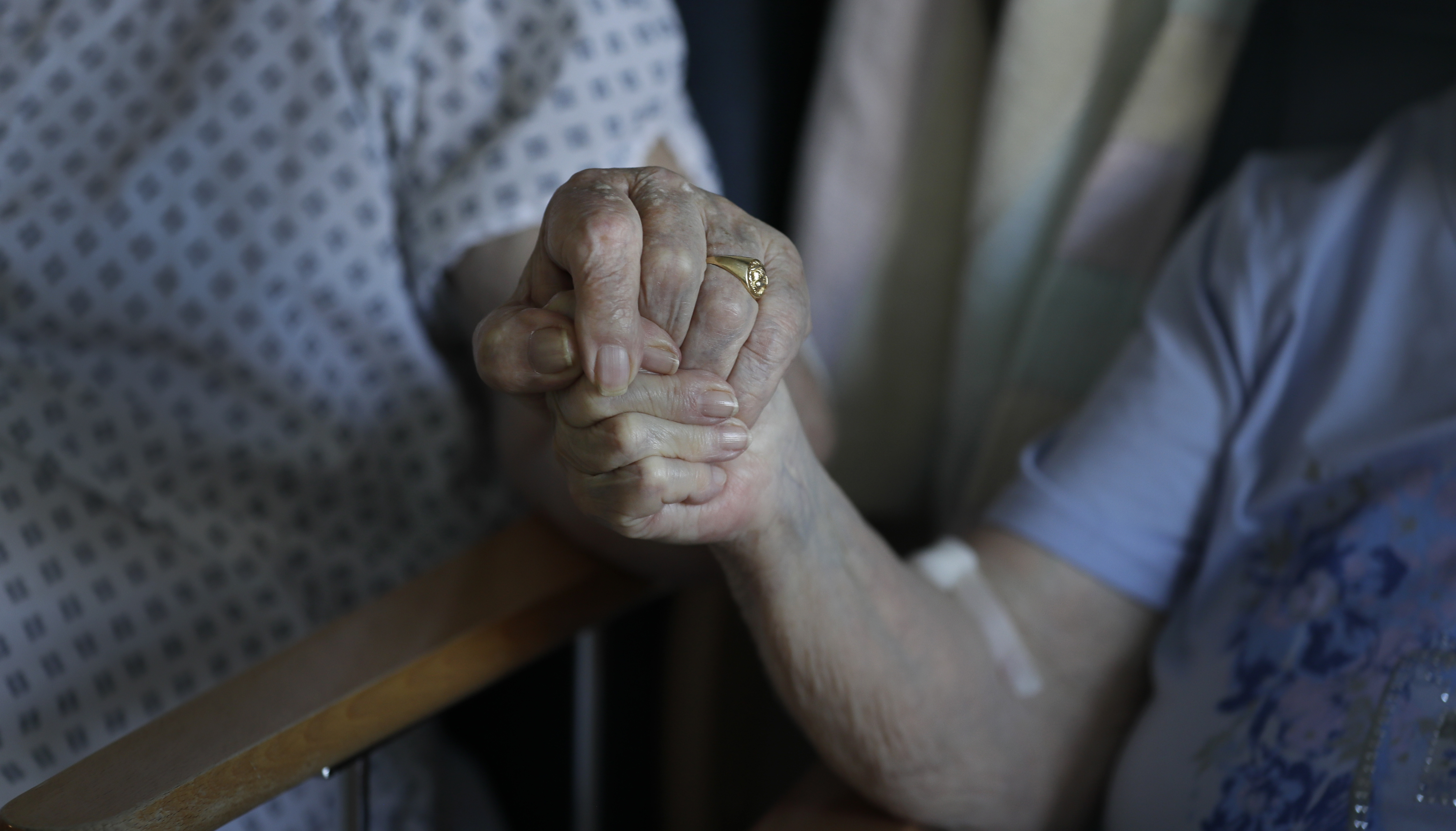 Two coronavirus patients hold hands during a short visit at a hospital in Cambridge, England [Getty Images]