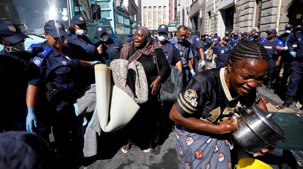 A woman wails as law enforcement officials move in to disperse a group of immigrants who had occupied a historic church and a square demanding to be moved to another country as they claimed to feel no