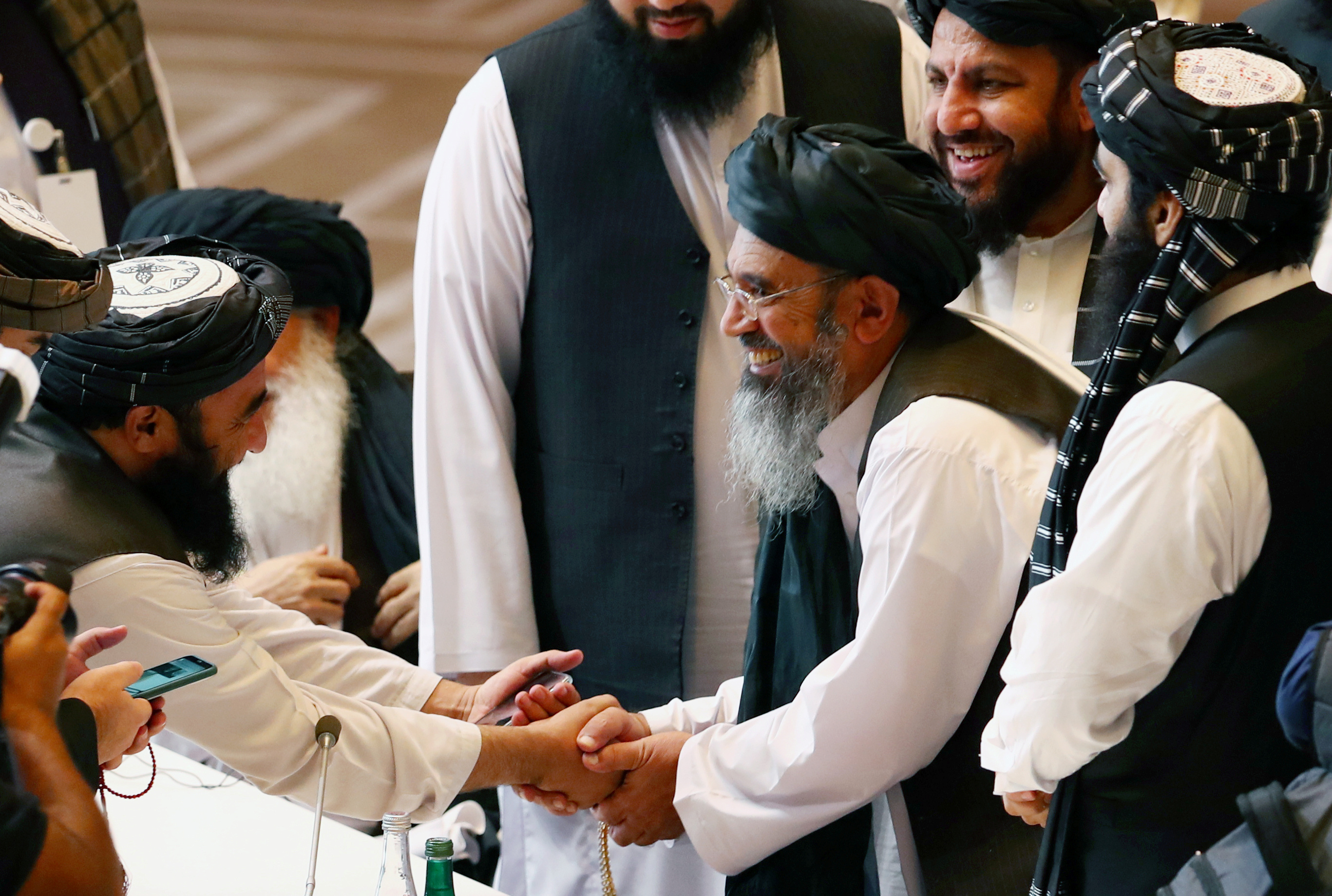Taliban delegates shake hands during the intra-Afghan talks in Doha, Qatar on September 12, 2020 [Ibraheem al Omari/Reuters]