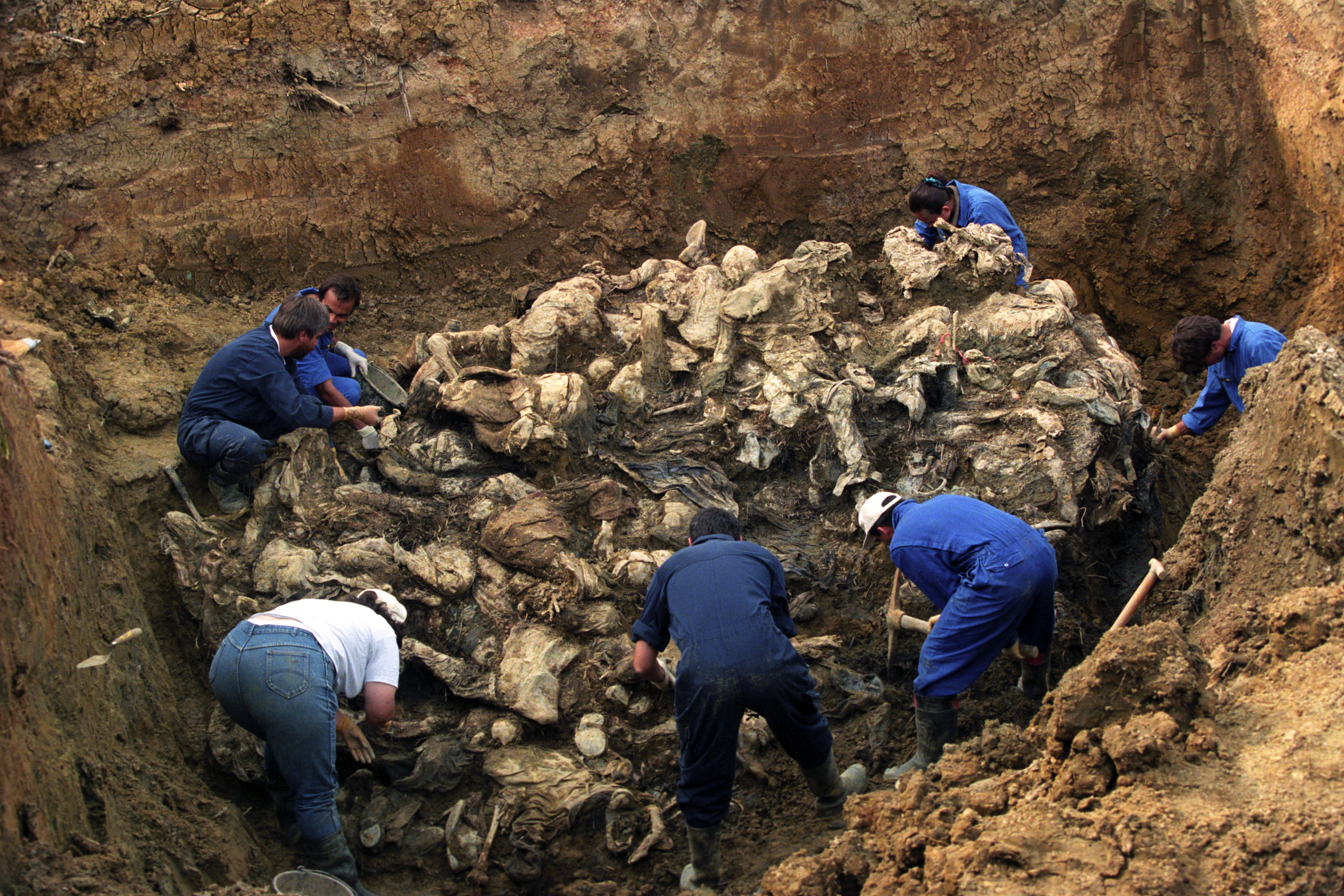 Investigators of the International War Crimes Tribunal work at a mass grave where they discovered the remains of more than 100 executed people outside the village of Pilica, Bosnia and Herzegovina, in September, 1996 [File: Odd Andersen/EPA-EFE]