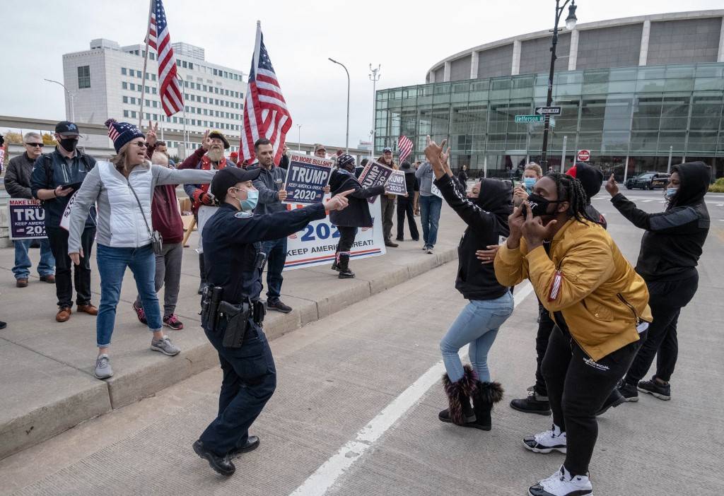 Counter protesters gesture at supporters of US President Donald Trump during demonstrations outside of the TCF Center in downtown Detroit, Michigan. Former vice president Joe Biden, making his third run at the White House, was tantalizingly close to victory as President Donald Trump sought to stave off defeat with scattershot legal challenges and his campaign insisted he would be reelected [Seth Herald/AFP]