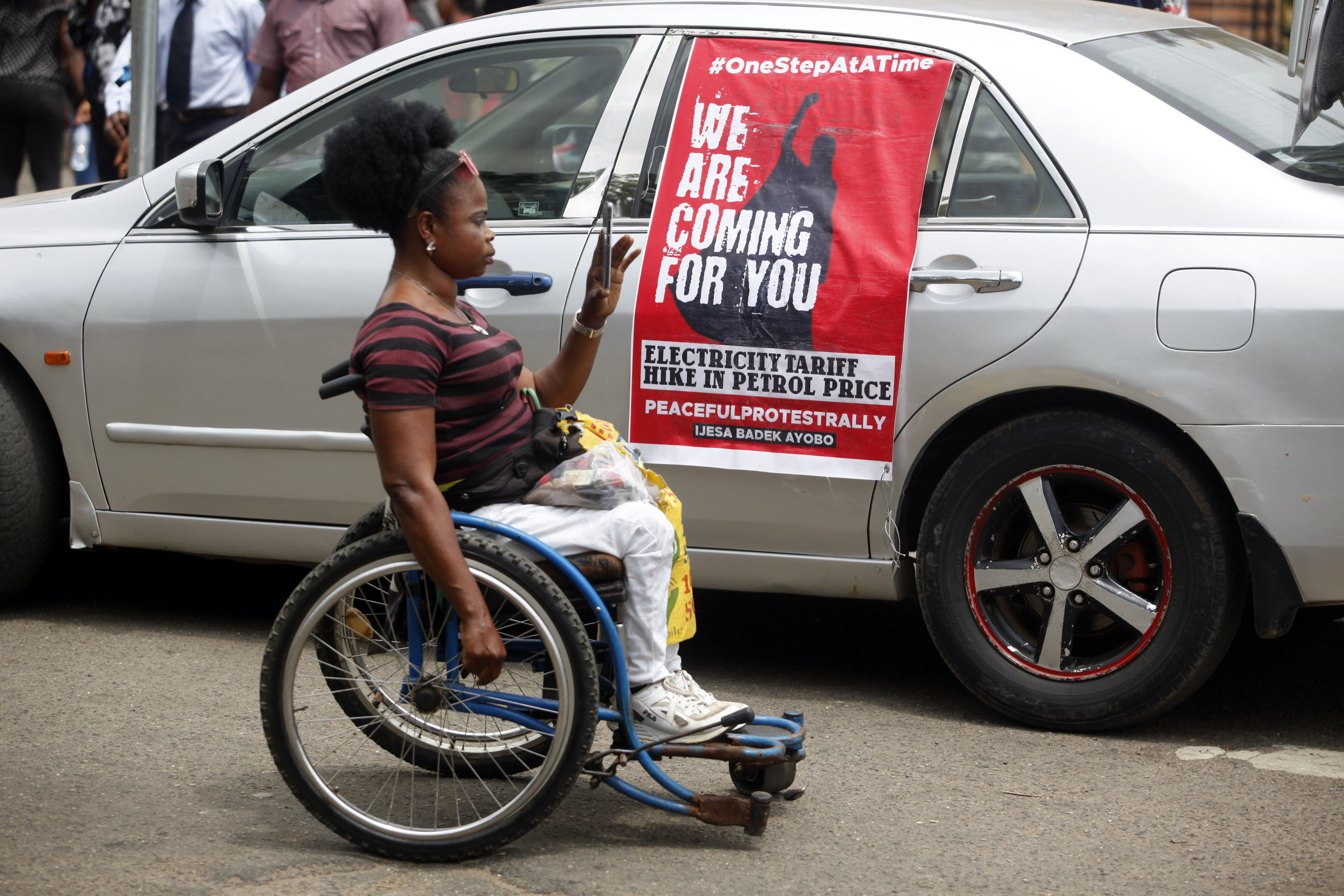 A woman takes a photograph with her mobile phone near a banner during a protest against the Special Anti-Robbery Squad (SARS), in the Ikeja district of Lagos, Nigeria on October 19 [File: Akintunde Akinleye/EPA]