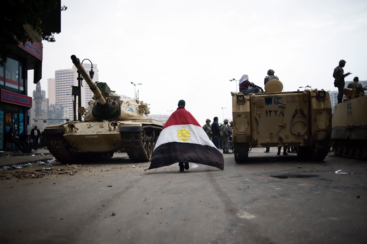 A protester walks between two army trucks as he enters Cairo's Tahrir Square on January 29, 2011 [Alessio Romenzi]