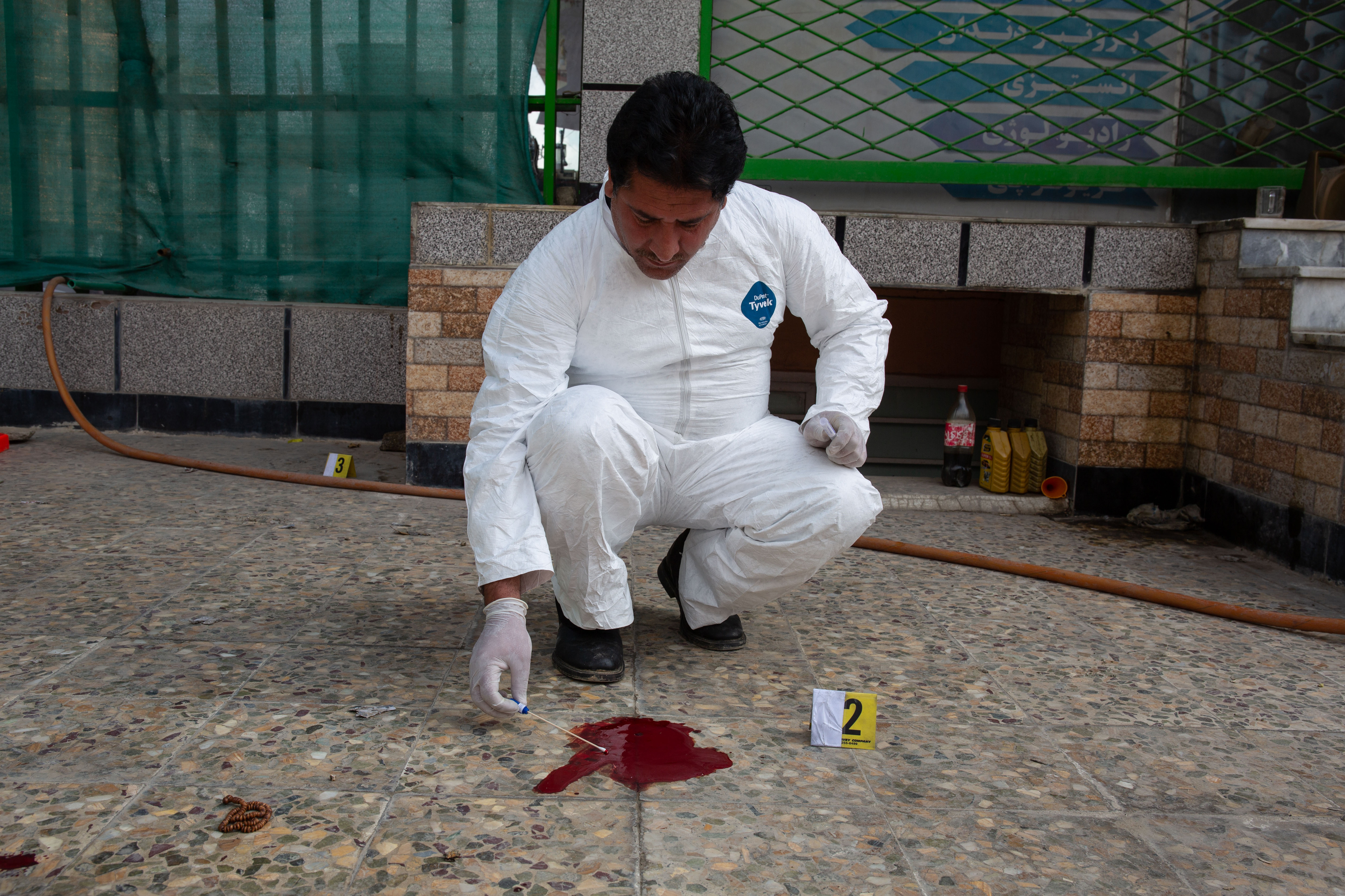 A member of the CSI team takes a sample of blood from a crime scene which will be sent to the Forensic Medicine Directorate (FMD) in Kabul for analysis [Lynzy Billing/Al Jazeera]
