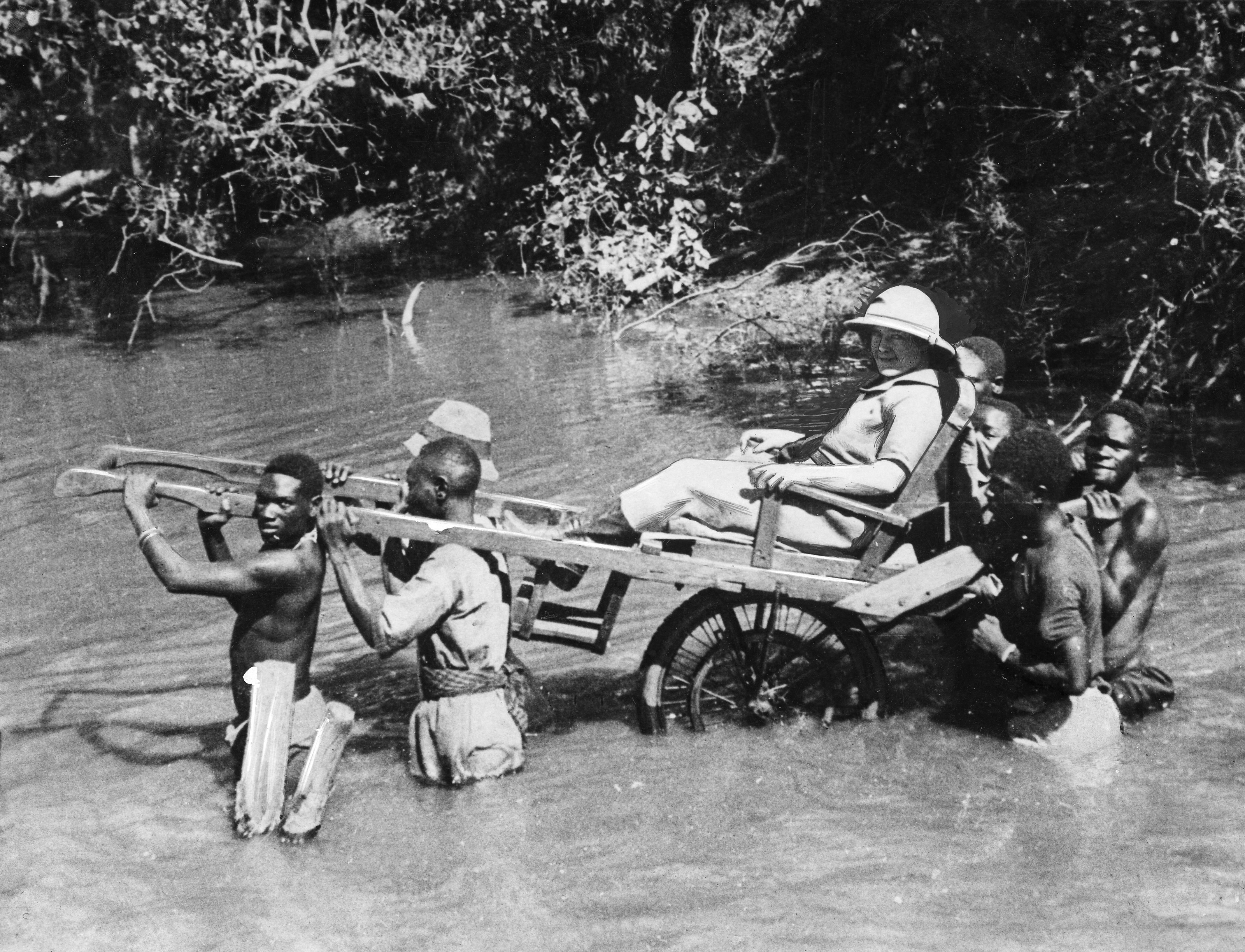 A file photo taken in Senegal, then a French colony, in the 1930s shows a European being carried through a river by African porters in a sedan chair [File: AFP]
