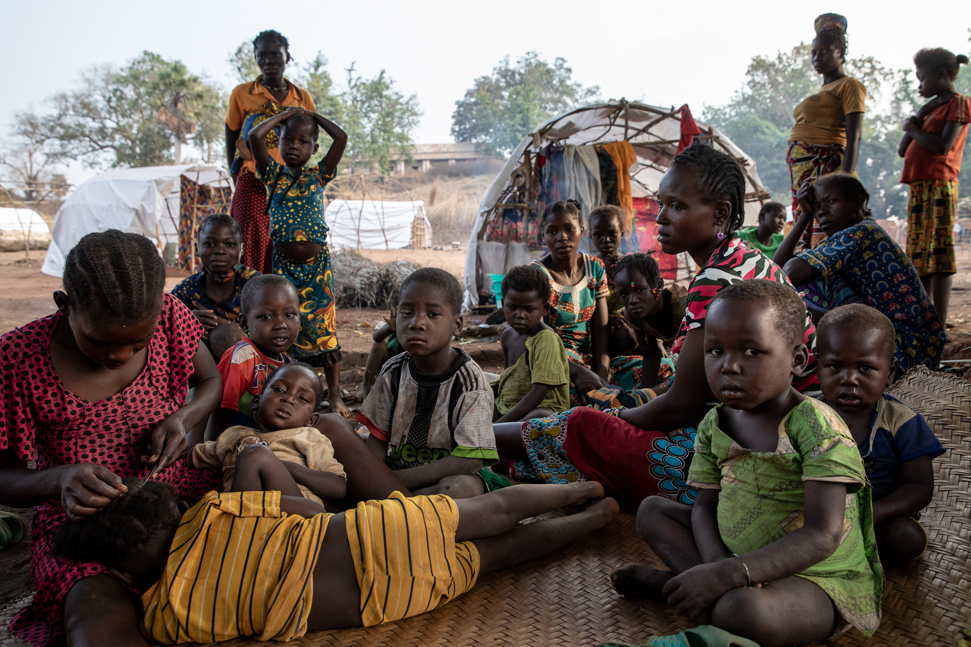 Women and children sit in the shade of a mango tree, in a Bouca IDP site. [Adrienne Suprenant/Al Jazeera]