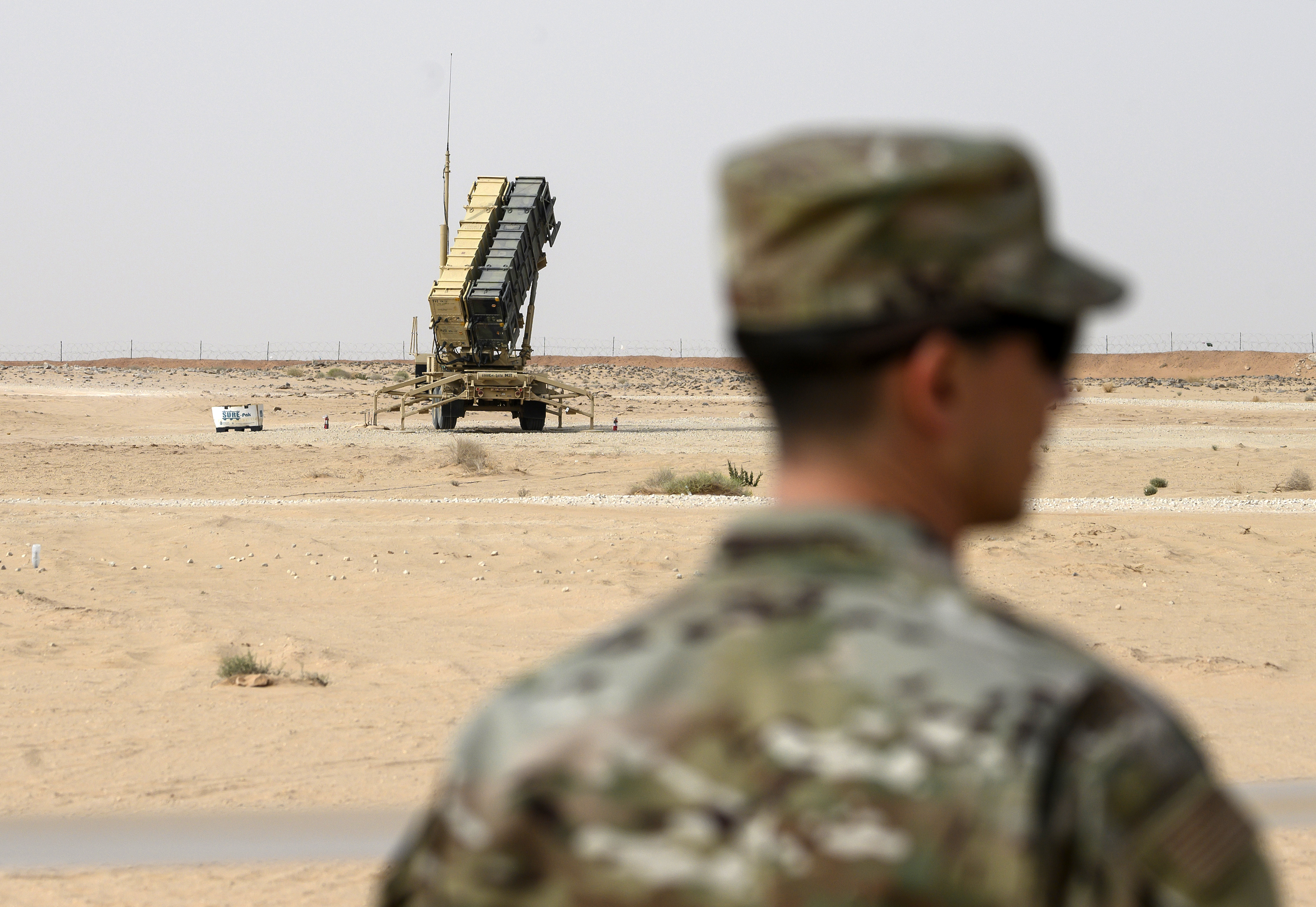 A soldier stands in the foreground with a US-made Patriot air-defence system