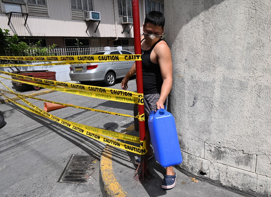 A Manila resident at a street entrance ahead of a lockdown in the Philippine capital as the number of new daily cases soars past 5,000 [Ted Aljibe/AFP]