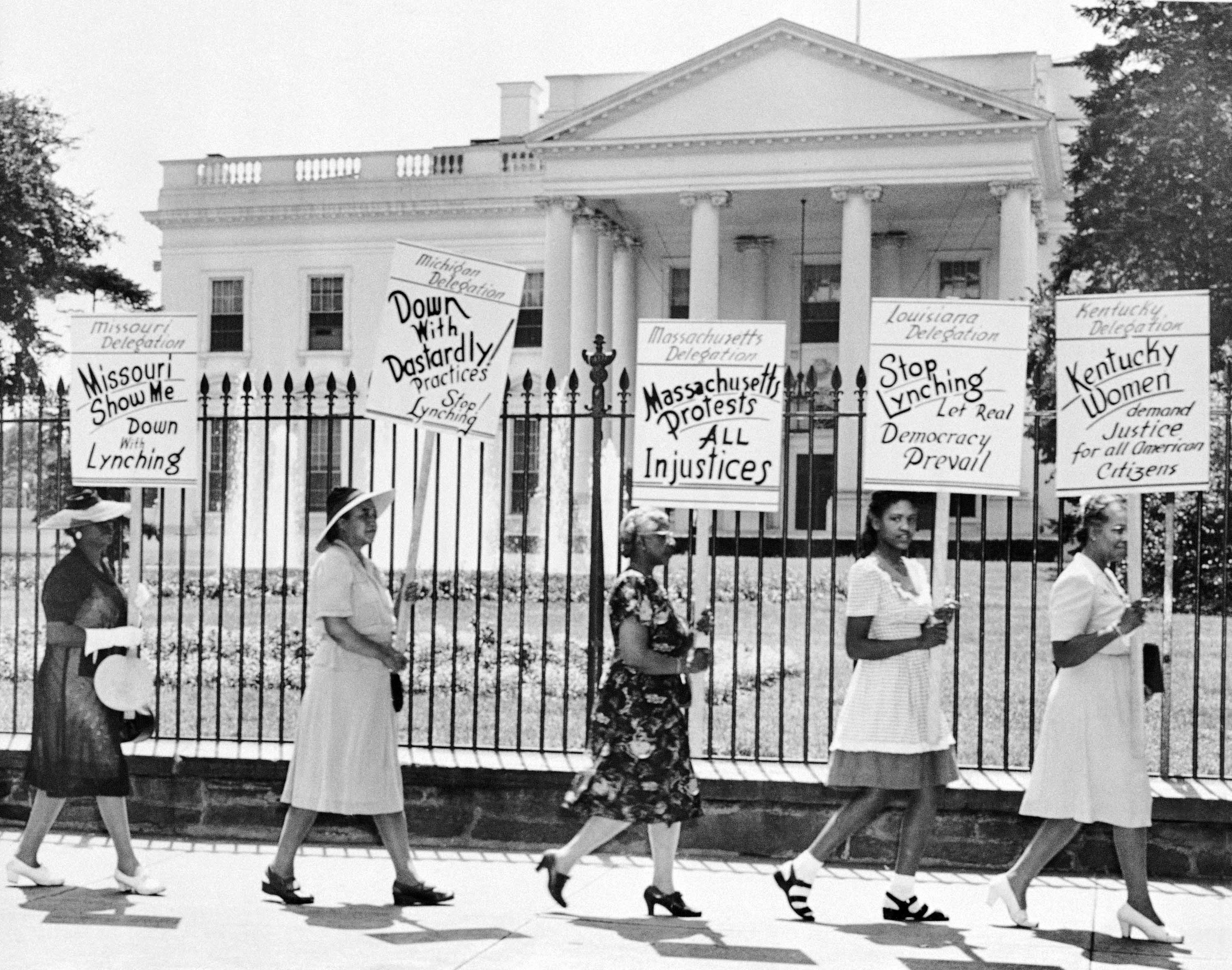 Picketers representing the National Association of Colored Women march past the White House in Washington, DC, July 30, 1956, carrying posters protesting the lynching of four Black people in Georgia [File: AP]