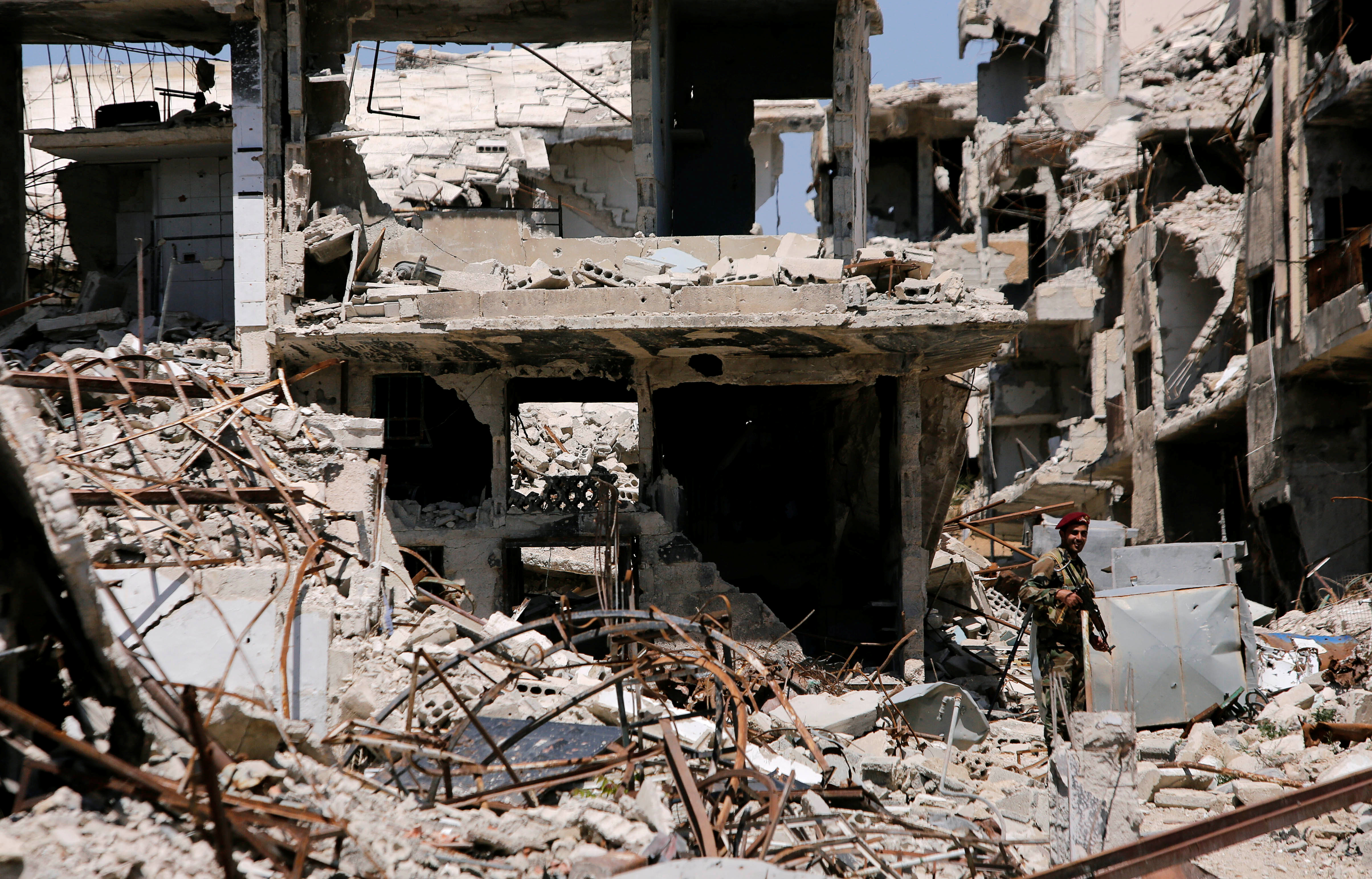 A member of Syrian forces of President Bashar al Assad stands guard in front of destroyed buildings in Jobar, eastern Ghouta, in Damascus, Syria April 2, 2018