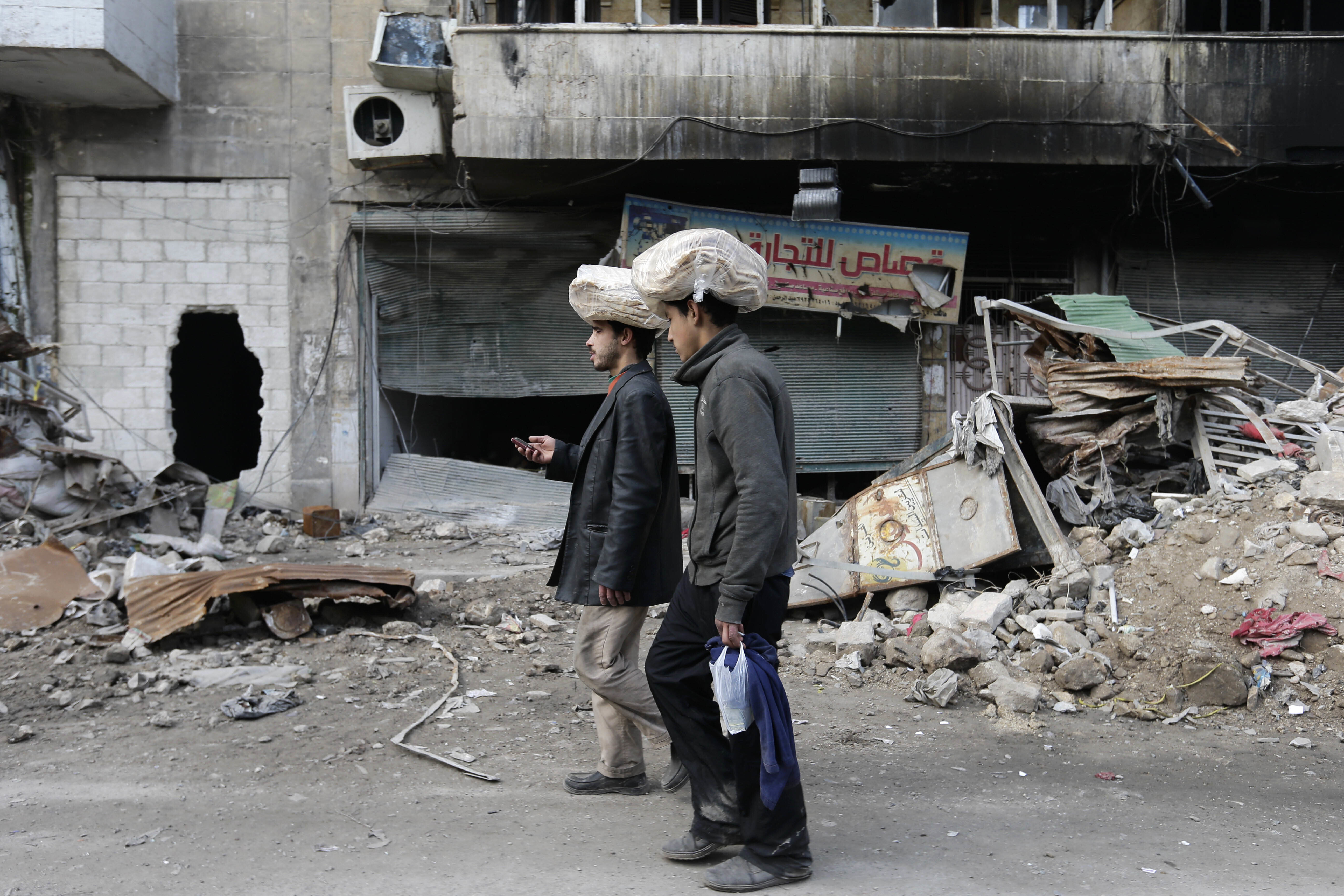 Syrian men carry bags of bread on their heads while walking back to their homes.
