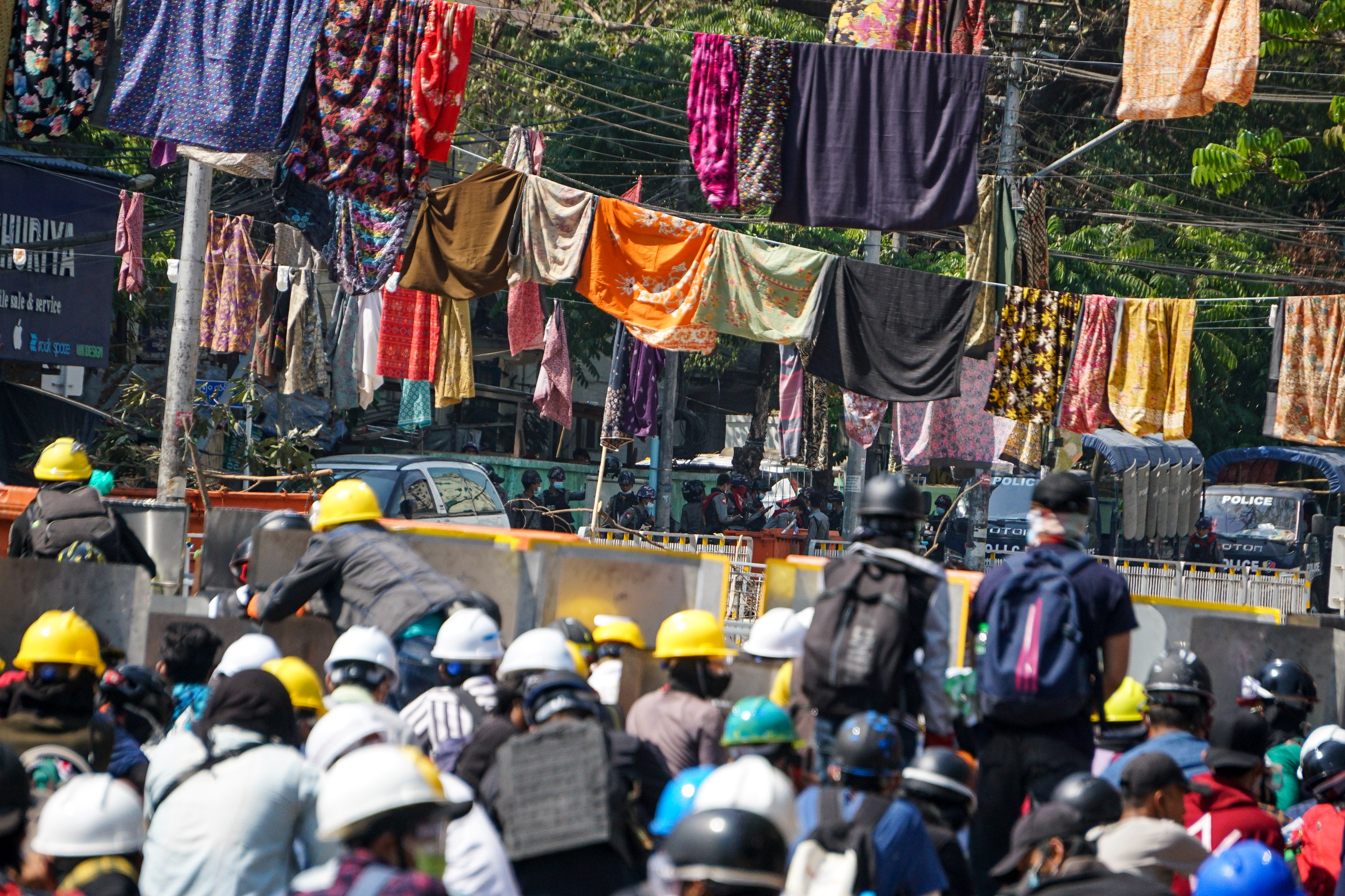 Protesters against the military coup in Myanmar are surrounded by women’s clothes which have been hung in the streets to keep soldiers and police away [Stringer/Anadolu]