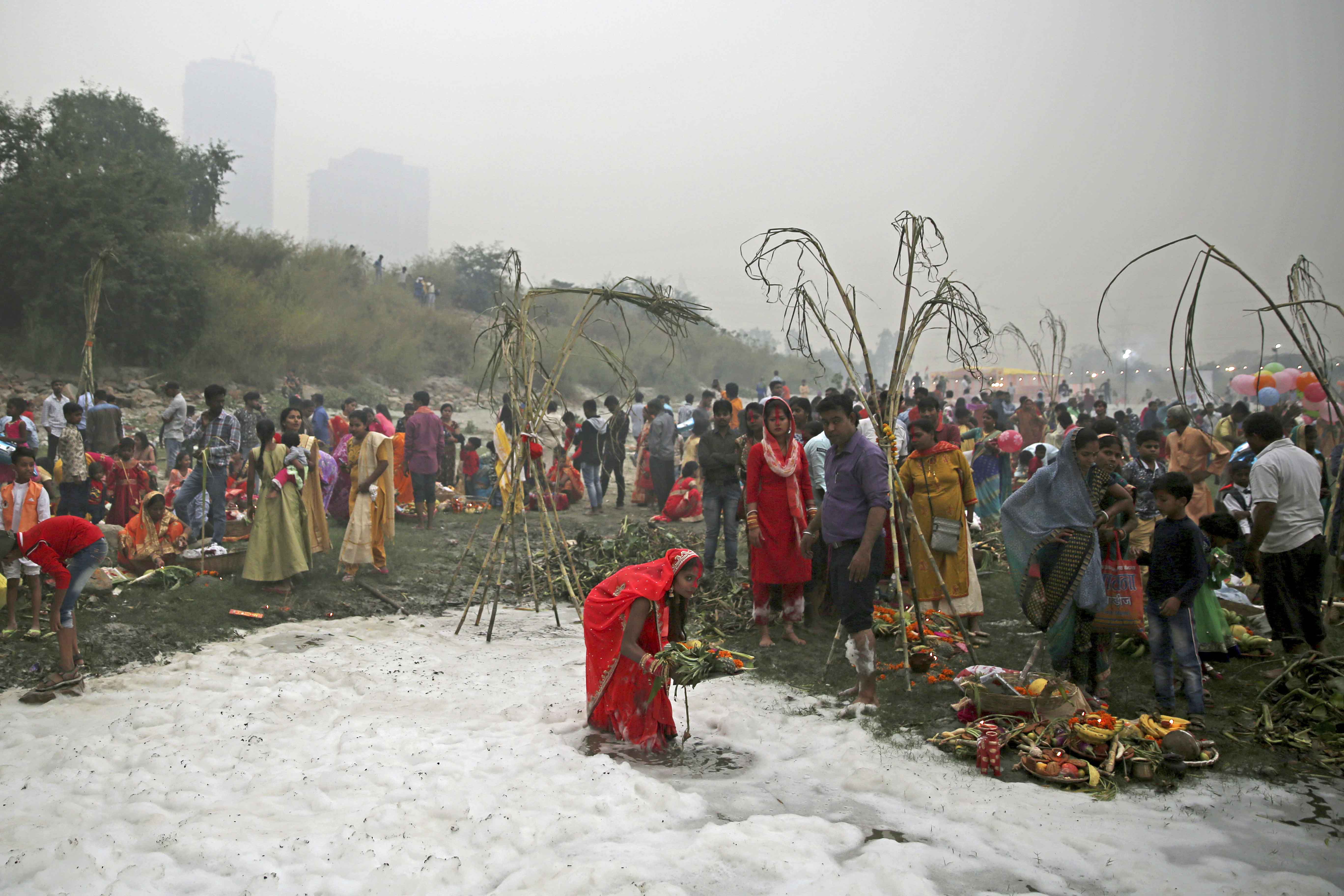 An Indian Hindu devotee performs rituals in the Yamuna river, covered by chemical foam caused due to industrial and domestic pollution, during the Chhath Puja festival in New Delhi, India on November 2, 2019 [File: Altaf Qadri/AP]