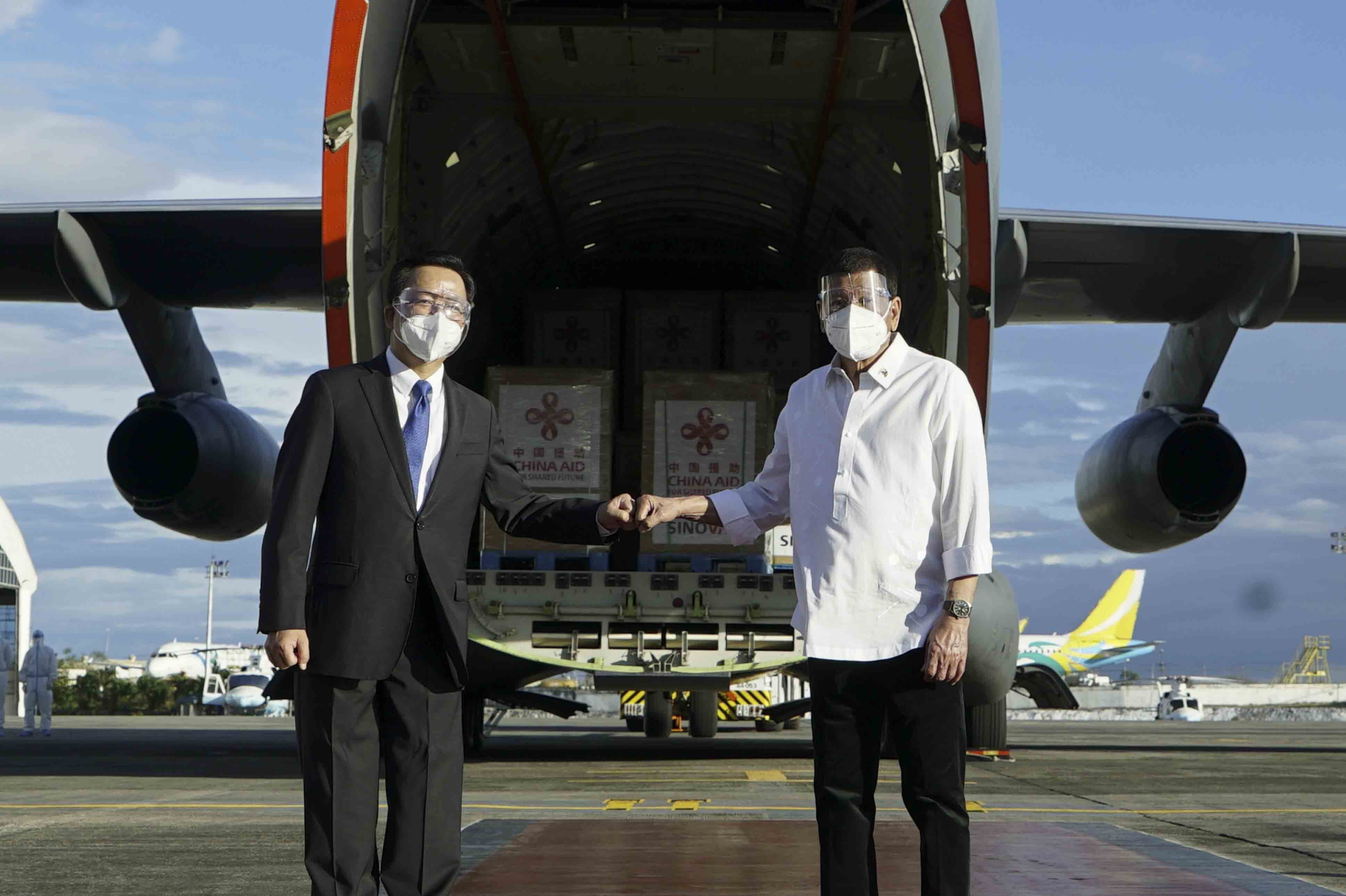 Philippine President Rodrigo Duterte, right, poses with Chinese Ambassador to the Philippines Huang Xilian in front of a military plane carrying Sinovac vaccines at the Villamor Air Base in Manila, Philippines on February 28, 2021 [File: King Rodriguez/Malacanang Presidential Photographers Division via AP]