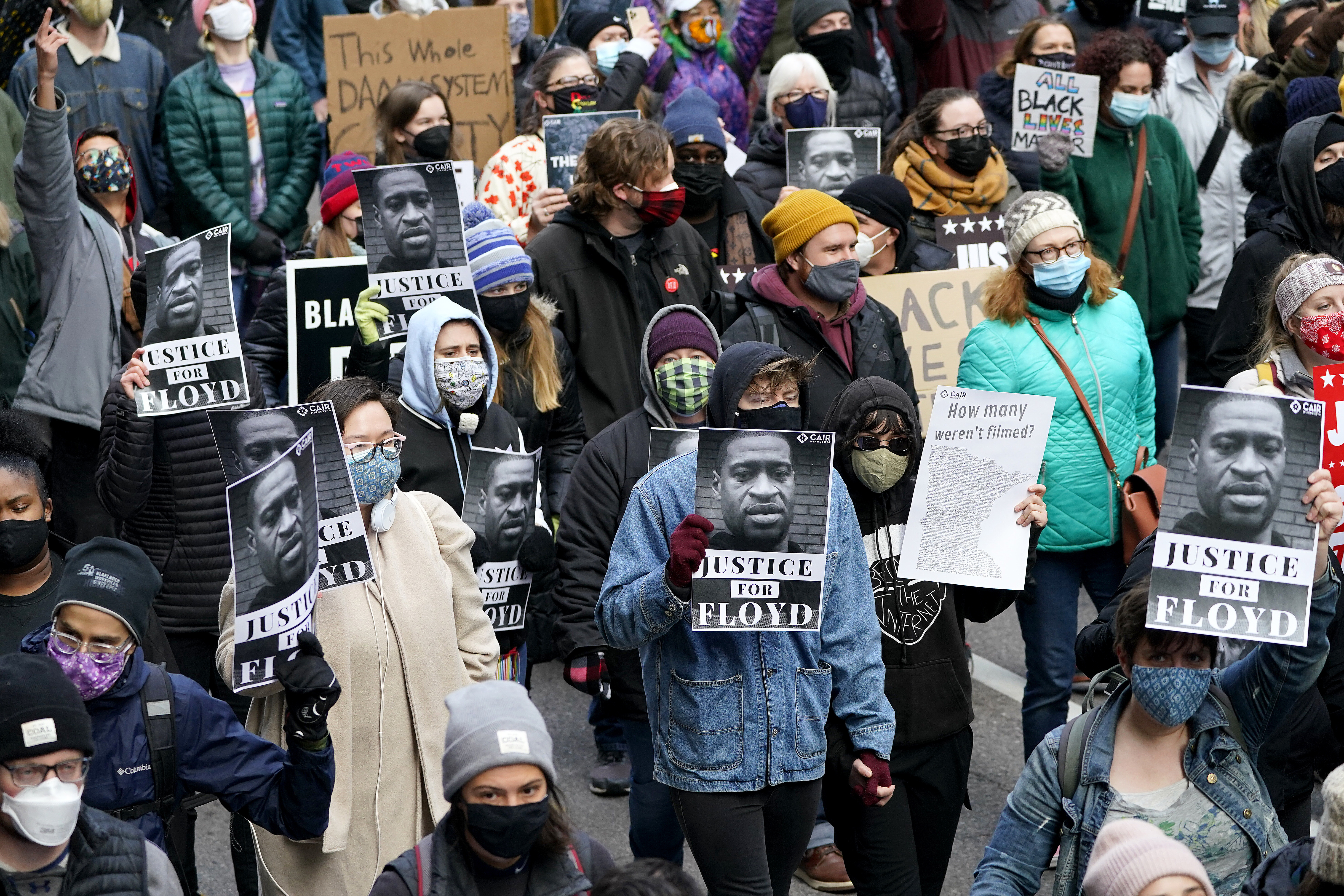People hold signs as they march near the Hennepin County Government Center during a rally in Minneapolis [Julio Cortez/AP Photo]