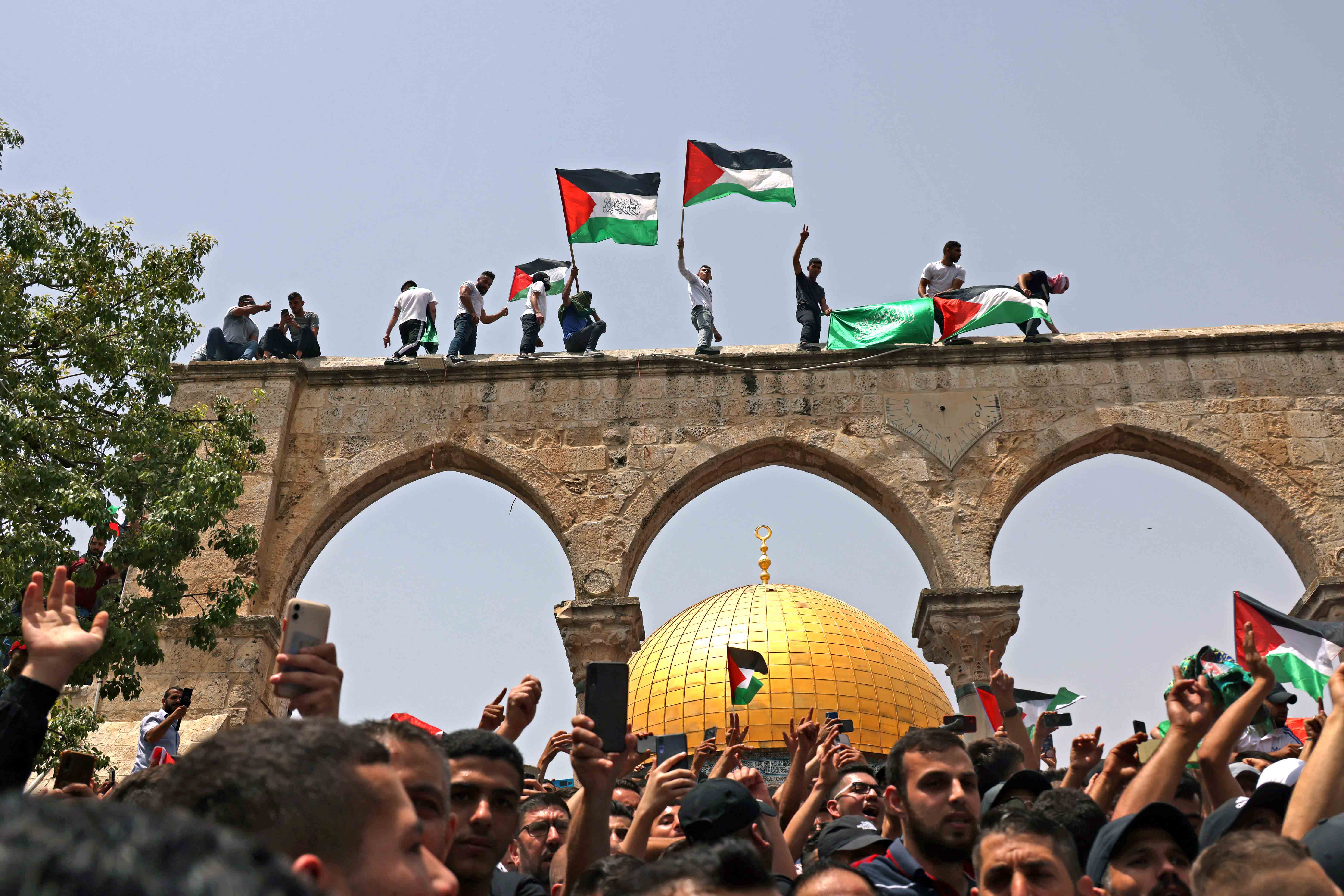 Palestinians wave the Palestinian flag at Al Aqsa Mosque in occupied Jerusalem on May 21, 2021 [Ahmad Gharabli/AFP]
